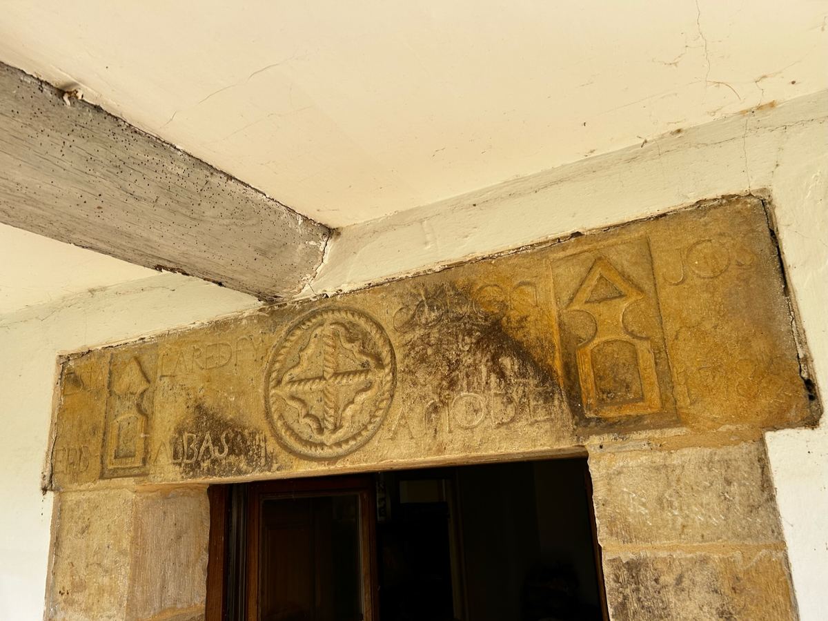 La piedra tallada sobre la puerta, con una cruz en un círculo y letras gastadas