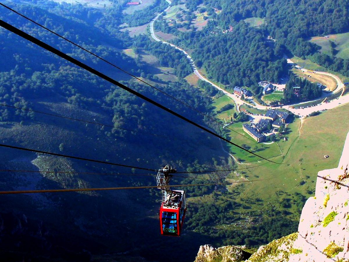 La cabina roja del teleférico de Fuente Dé sobre el valle, muy por encima de los prados